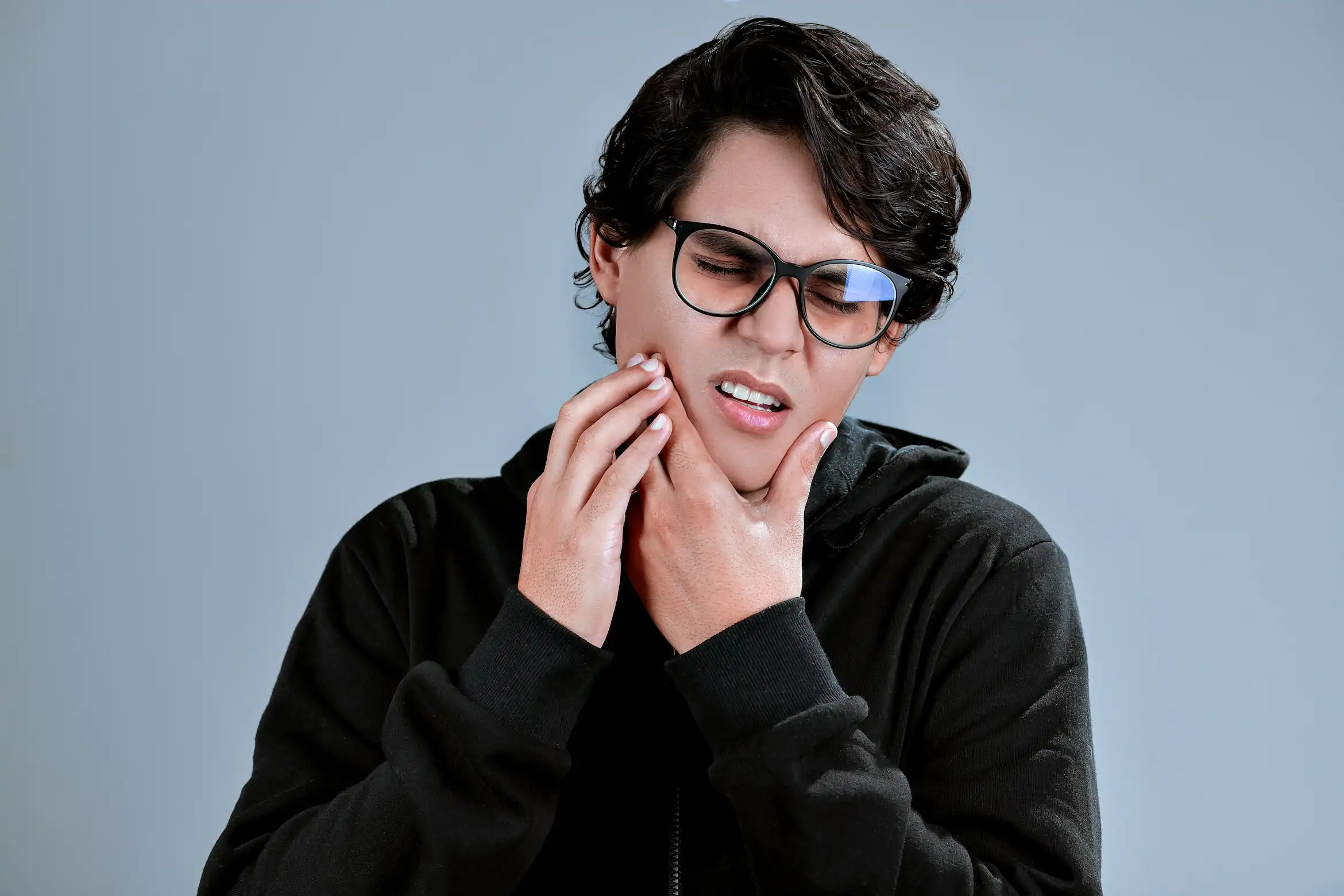 صورة لشخص يضع يده على خده لمقالة عن اسباب حساسية الاسنان