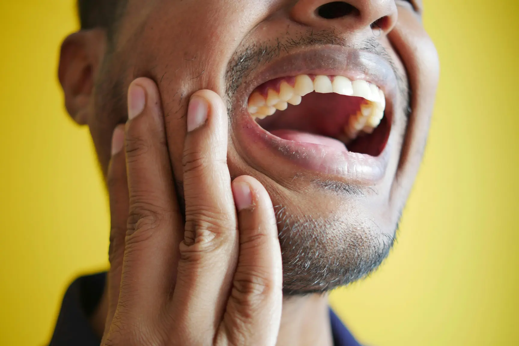 صورة رجل يضع يده على خده فاتحًا فمه لمقالة عن التهاب سقف الحلق