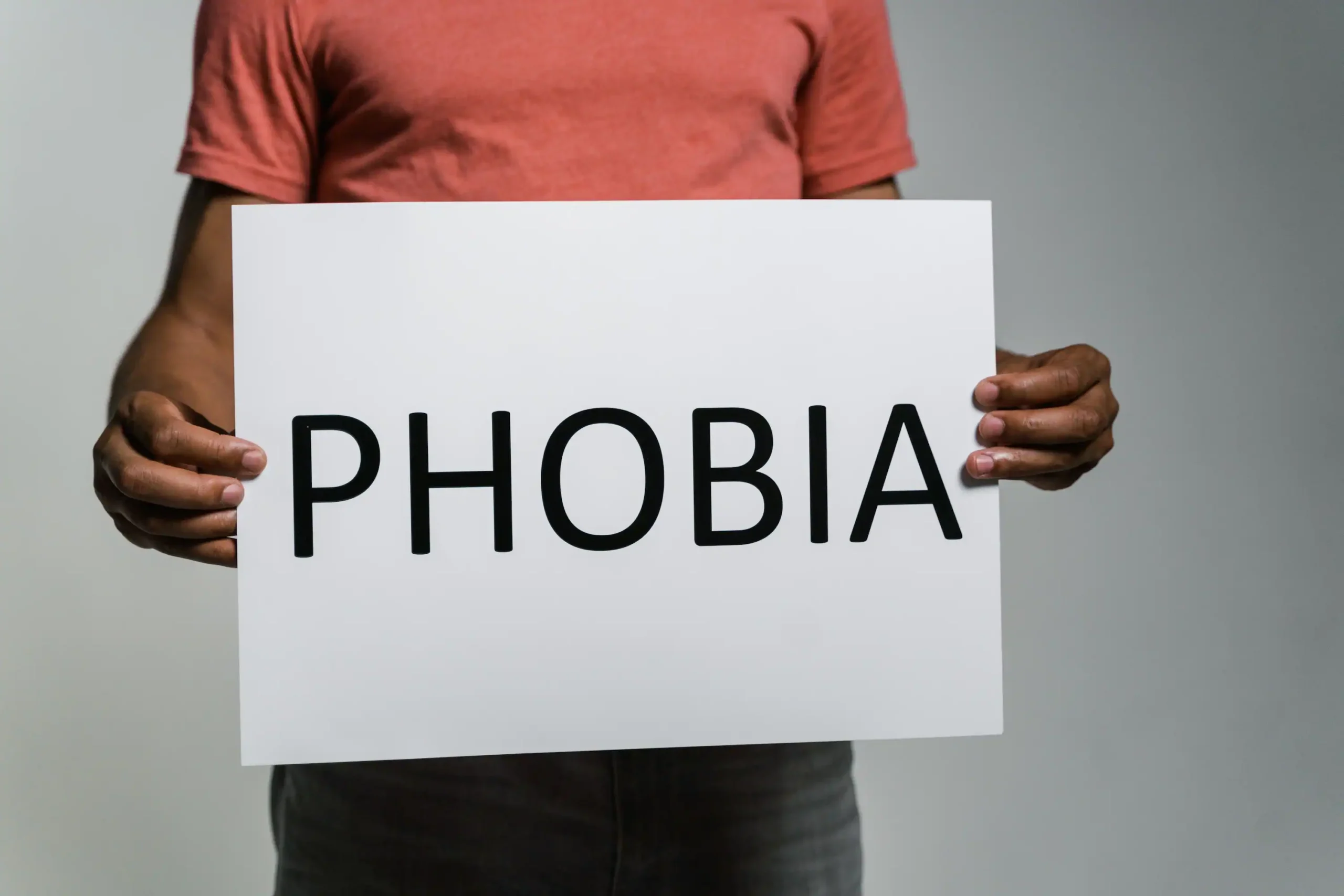 cover image for a blog about dental phobia showing a person holding a sign that says "PHOBIA"