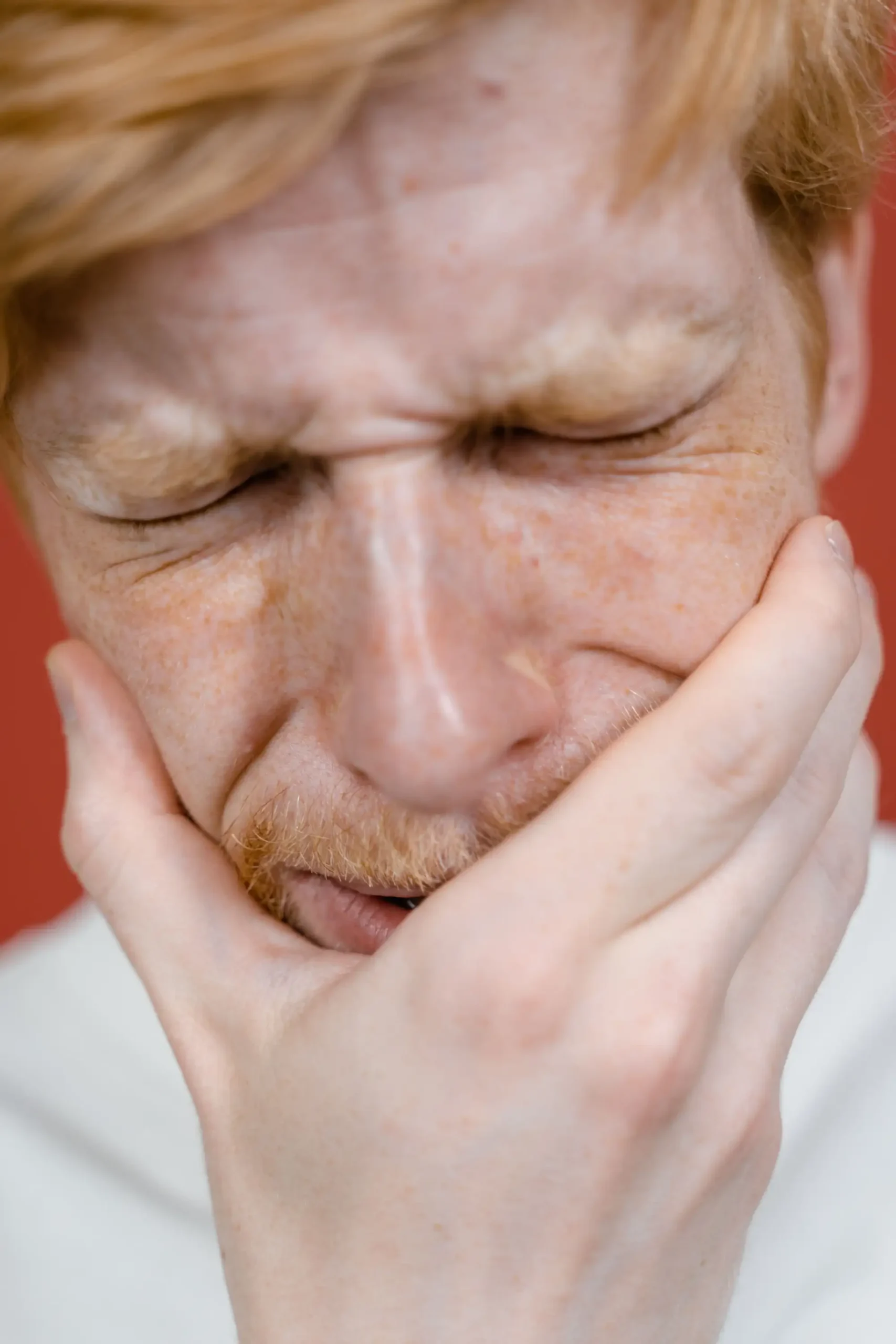 an image of a man holding his mouth in pain